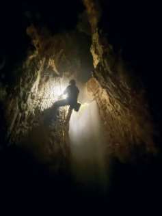 Speleologo in traverso accanto alla cascata, silhouette controluce