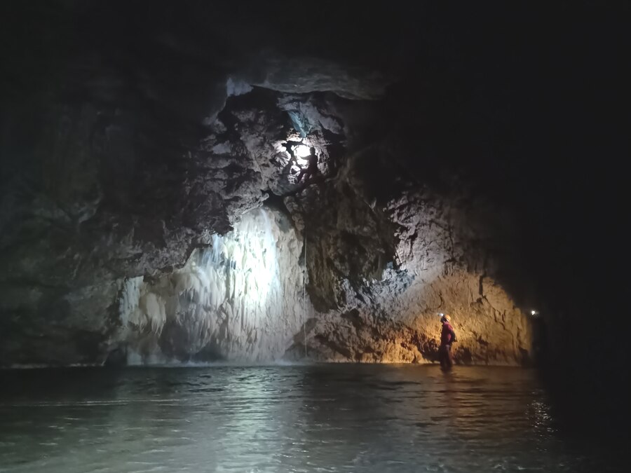 Una delle cascate della Grotta dello Scalandrone, con uno speleologo che ne osserva la base