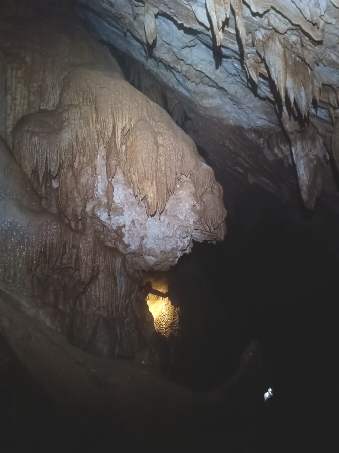 Speleologo in progressione su corda, illuminato in un ambiente riccamente concrezionato